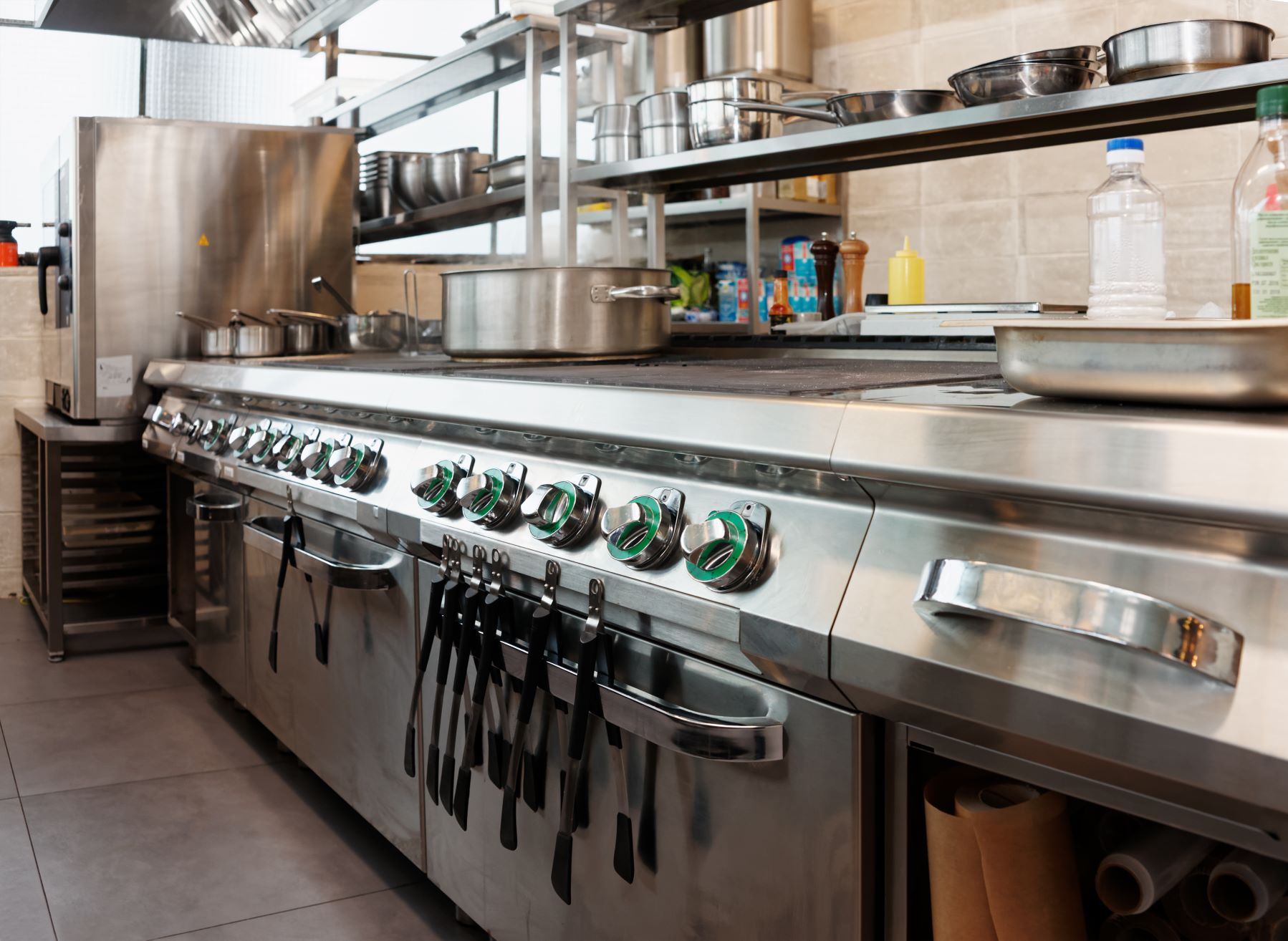 commercial restaurant kitchen line with cooking equipment, pots and pans, ovens, stovetops