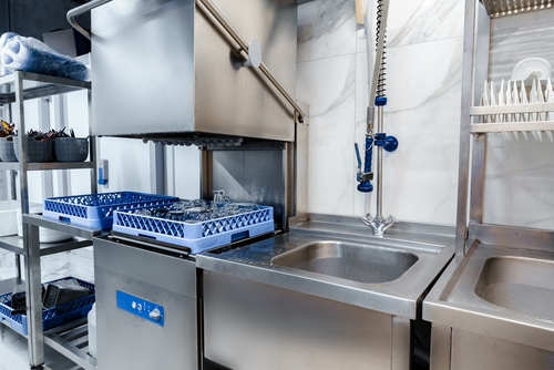 commercial dishwasher with racks and kitchen cleaning equipment in a restaurant kitchen